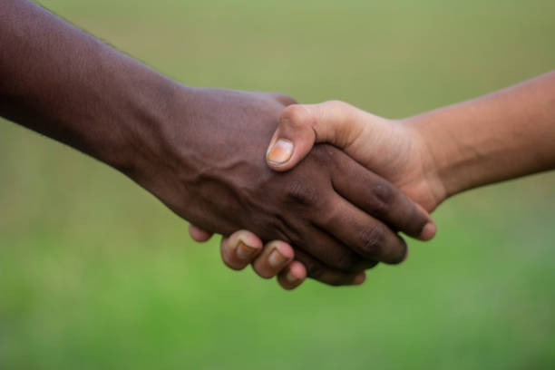 istock A white man and a black man shaking hands together with their hands as they meet 1497356962