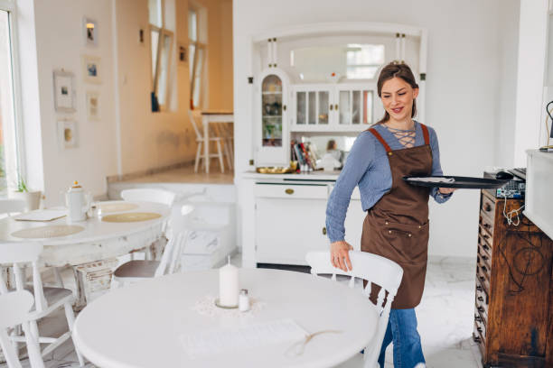 istock Smiling waitress with an apron is working in a restaurant, cleaning the tables 1497357143