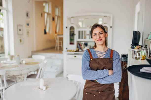 istock A cheerful waitress in an apron looks directly into the camera while standing in the restaurant where she works 1497357192