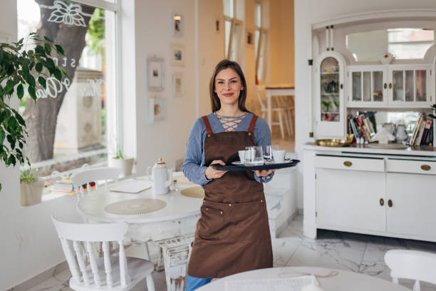 istock Smiling waitress holding tray and delivering drinks ordered by restaurant guests 1497357307