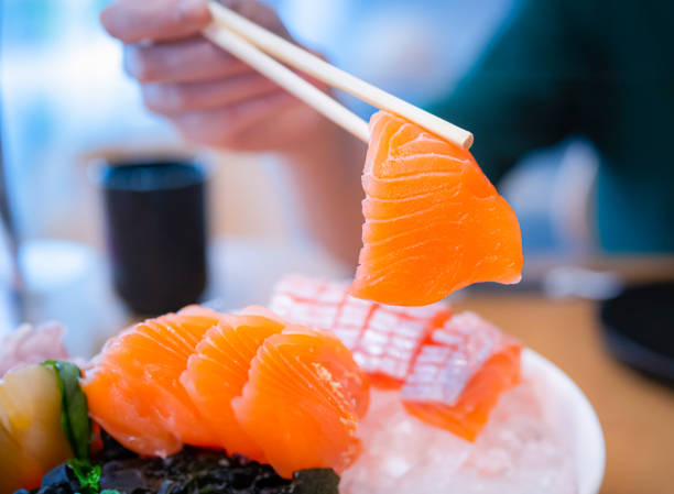 istock Using chopsticks, salmon sashimi. Sashimi is a popular dish of Japanese restaurants. 1497362028