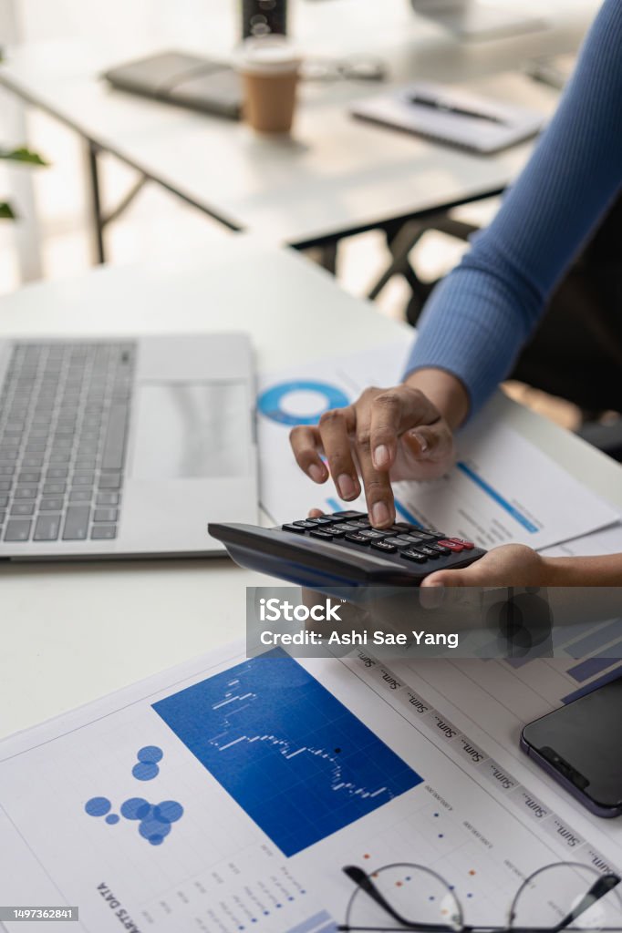 Accountant using risk management process calculator with running market reports, touchscreen documents, tablets, using graphic icons, global stock market reports, starting business projects. Vertical Risk Management Stock Photo