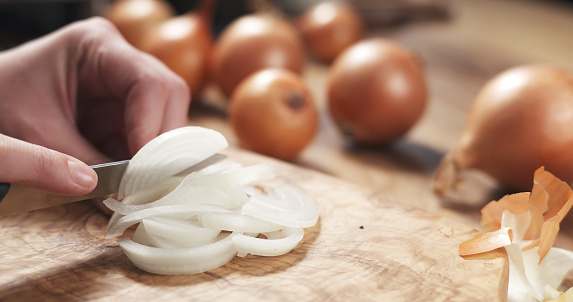 young female hands slicing white onion, wide photo
