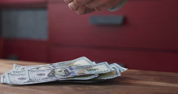 istock side shot of man counting dollars on wood table 1497365700
