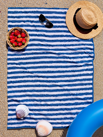 Towel on beach sunhat seashell hat sunglasses strawberries floatie