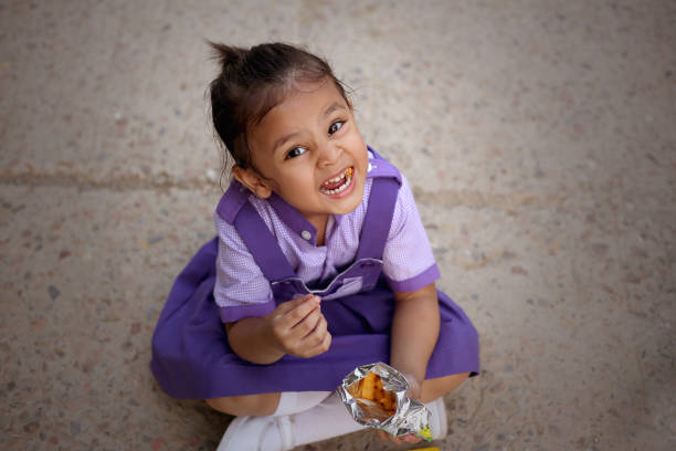 Young girl sitting at a colorful playground table, playing with small stones