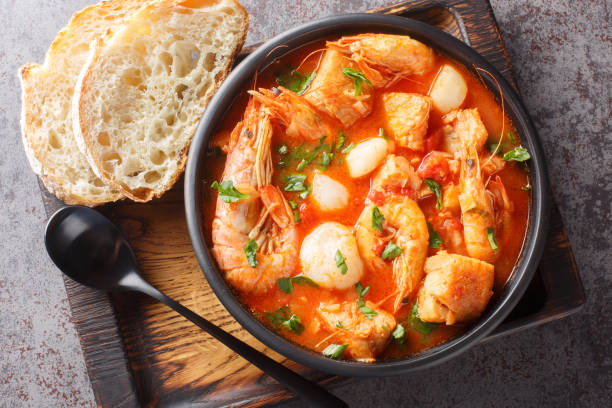 Mediterranean soup of seafood and white fish with shrimp, mussels, scallops, squid close-up in a bowl. horizontal top view stock photo