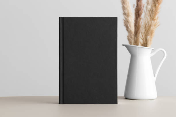 istock Black book mockup with a pampas decoration on the beige table. 1497379962