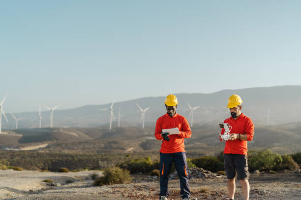 istock Drone engineers working on wind turbine farm - Alternative energy and aerial engineering concept 1497387283