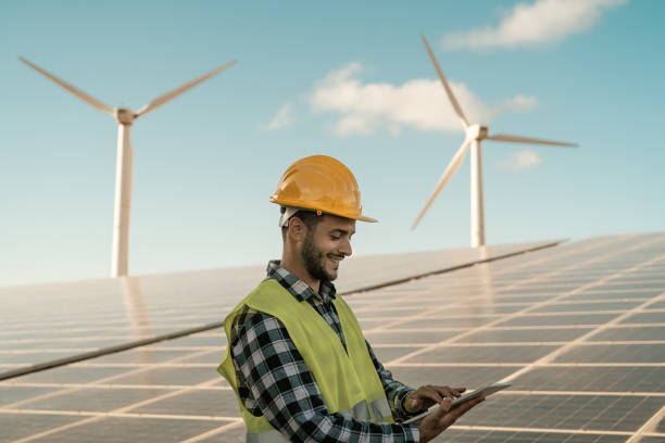 istock Young engineer watching on digital tablet the new green plan for alternative energy with wind turbine and solar panel - Innovation and green power concept 1497388306