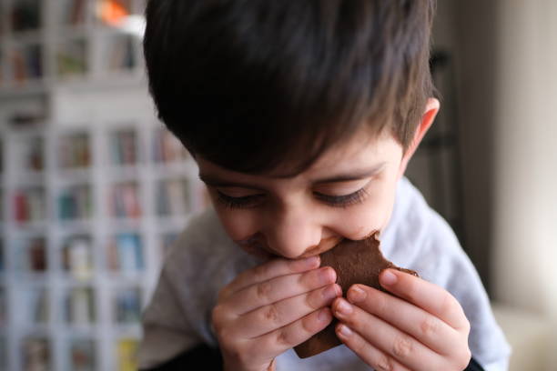 Smiling little boy licking messy chocolate from his face