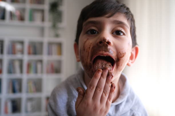 istock Smiling little boy licking messy chocolate from his face 1497390936