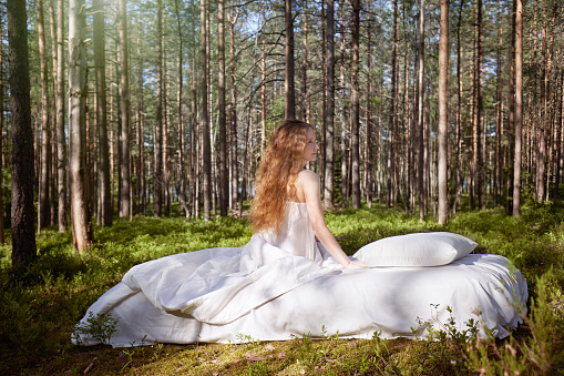 Woman sleeps on a mattress in the summer forest. The girl is resting in nature
