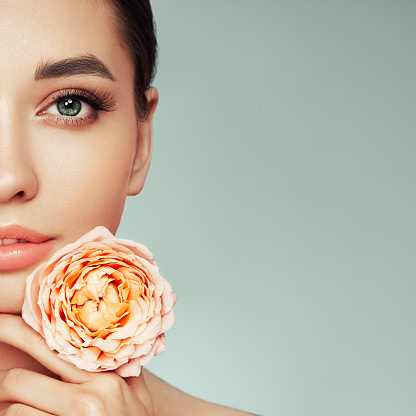 Portrait beautiful young woman with clean fresh skin. Model with healthy skin, close up portrait. Cosmetology, beauty and spa. Girl with a rose flower