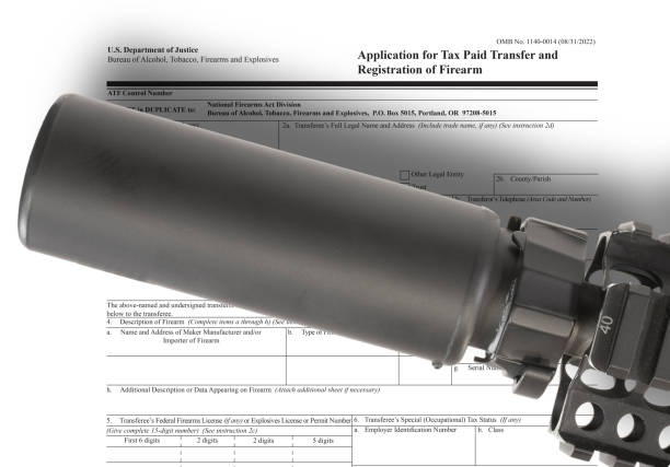 Public domain ATF form to own a suppressor in the background with silencer above Public domain ATF silencer ownership form with a silencer and drop shadow mounted on an assault rifle above public domain images stock pictures, royalty-free photos & images