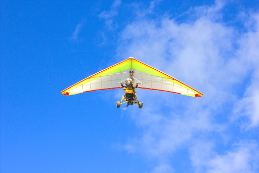 On a clear sunny day, a high-flying hang glider is clearly visible in the sky.