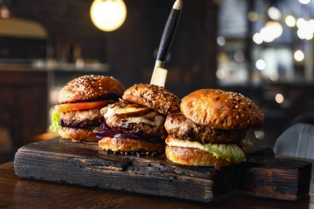 three different brutal burgers on wooden board in burger joint