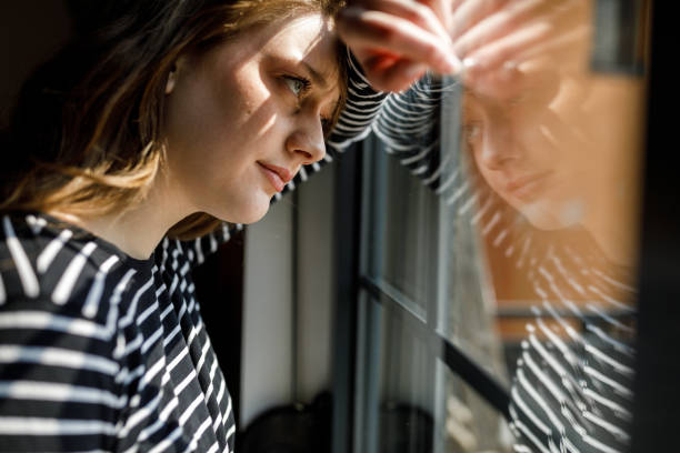 istock Anxious young woman standing by the window, contemplating 1497397320