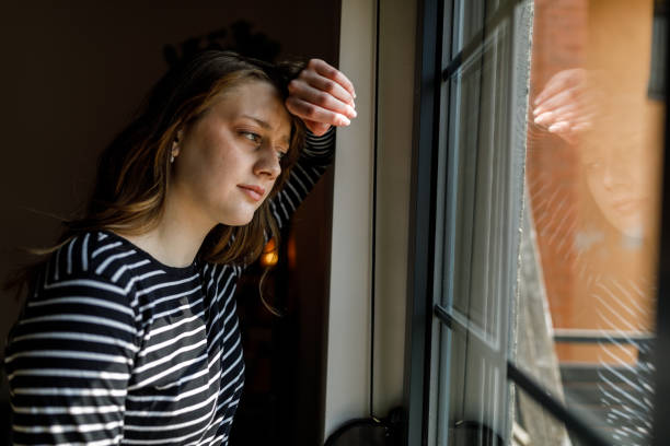 istock Anxious young woman standing by the window, contemplating 1497397336