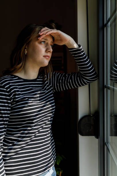 istock Anxious young woman standing by the window, contemplating 1497397348
