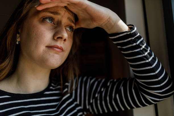 istock Anxious young woman standing by the window, contemplating 1497397370