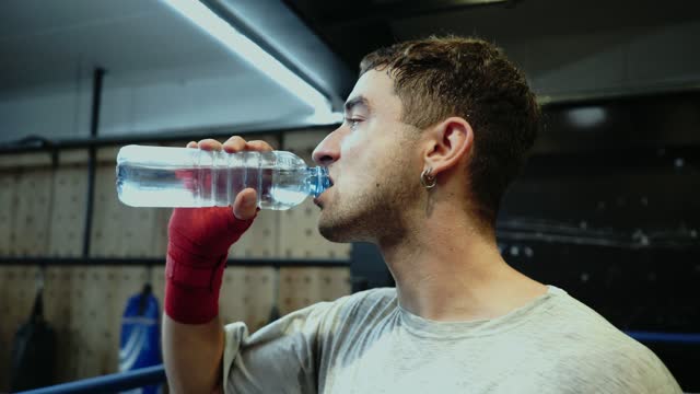 Young man drinking water at the gym