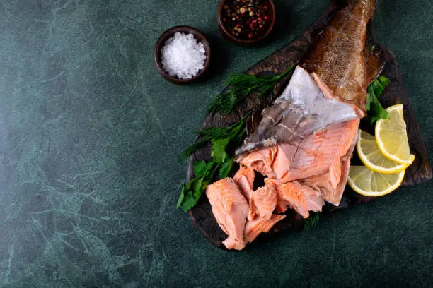 Photo of Hot smoked trout fillet on dark green table