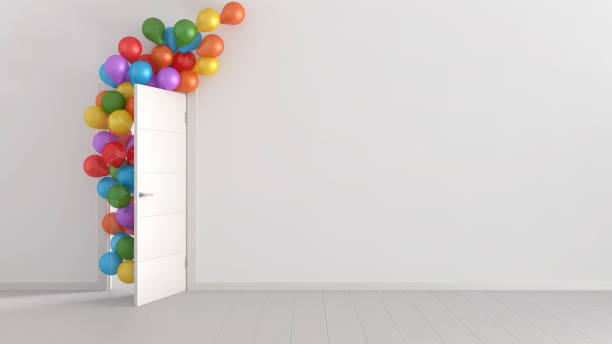 Colorful balloons floating through open door in home interior with white walls and parquet. Template with copy space. Surprise holiday concept stock photo