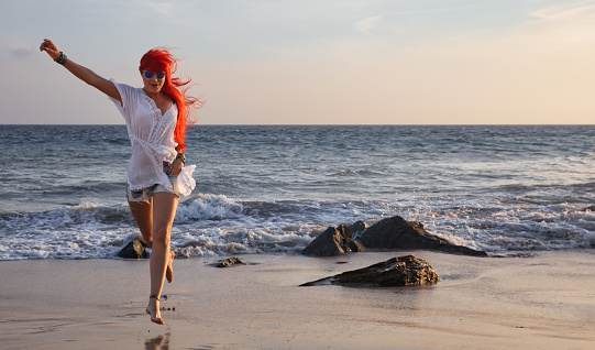 Happy red-haired young woman enjoys her tropical beach vacation