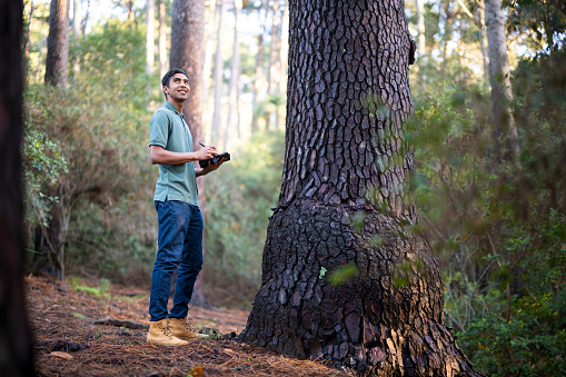Young man using technology in forest for scientific research supporting a sustainable supply chain.