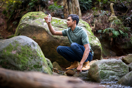 Young man using technology in forest for scientific research supporting a sustainable supply chain.