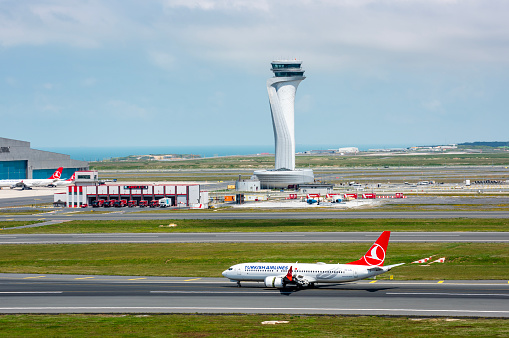 Istanbul, Turkey - June 3, 2023: Turkish Airlines airplane with Air Traffic Control Tower of Istanbul Airport. View of international Istanbul New Airport.