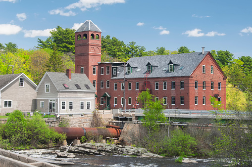 the old historic Sparhawk Mill located on the Royal River on a sunny blue sky day in Yarmouth Maine.