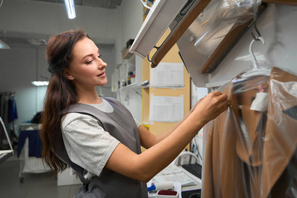 istock Woman dry-cleaner operator putting tag on plastic bag with coat 1497420839