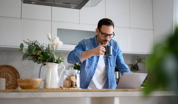 istock Male entrepreneur freelancer having coffee and using a laptop on kitchen counter at home office 1497421147