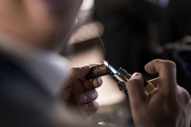 A man lights a cuban cigar A man lights a cuban cigar cigar stock pictures, royalty-free photos & images
