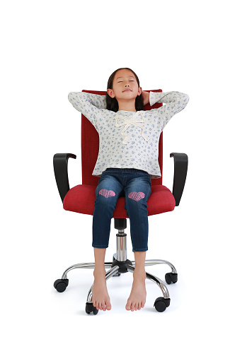Smiling Asian little girl child sitting and relax on chair isolated on white studio background. Image full length with Clipping path