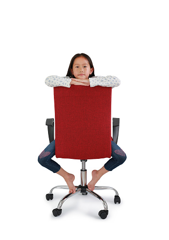 Little Asian girl kid riding on red chair with looking at camera isolated on white background. Image with Clipping path.