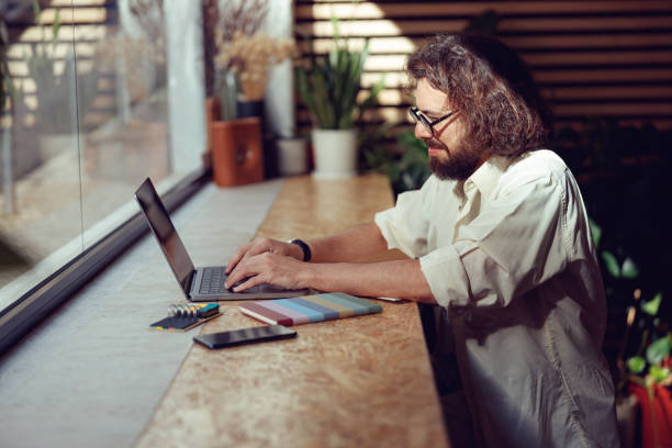 istock Focused male freelancer working on laptop while sitting in modern coworking. Remote work concept 1497433264