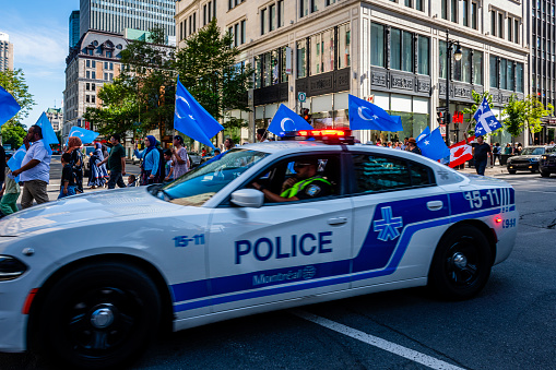 Montreal, Canada - August 28, 2022: some people making a demonstration with uygur flags in downtown Montreal. Police is driving by.