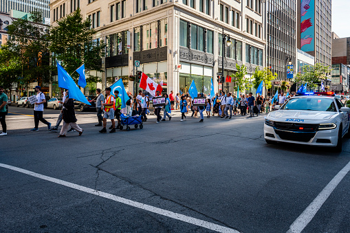 Montreal, Canada - August 28, 2022: some people making a demonstration with uygur flags in downtown Montreal. Police is driving by.