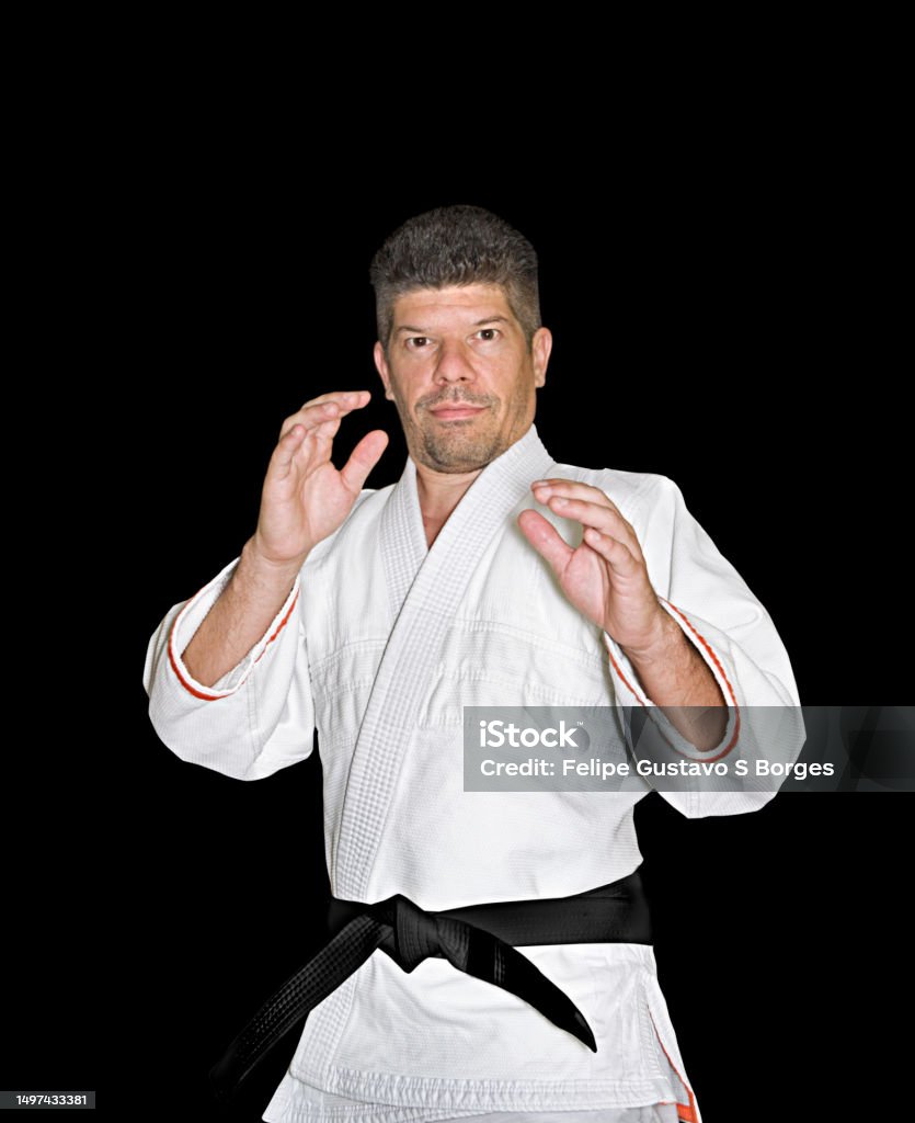 Martial arts practitioner wearing white kimono and black belt demonstrating defense stance Jiu Jitsu practioner ewaring typical gi Jujitsu Stock Photo
