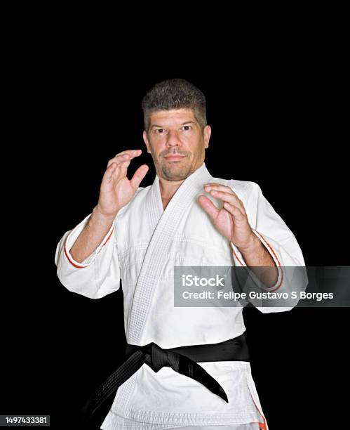 Martial Arts Practitioner Wearing White Kimono And Black Belt Demonstrating Defense Stance Stock Photo - Download Image Now
