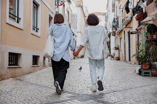 Back view of couple walking on Lisbon street, enjoying sightseeing outdoors . High quality photo