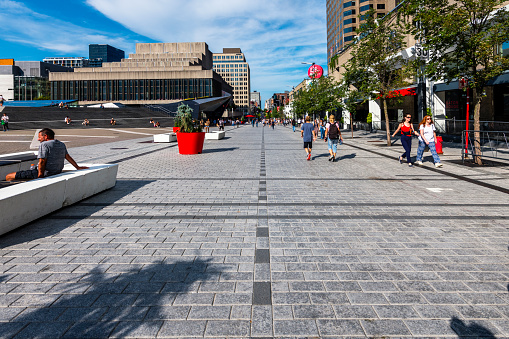 Montreal, Canada - August 28, 2022: people walking along a shopping street with a lot of stores and shops in Montreal