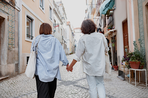 Back view of couple walking on Lisbon street, enjoying sightseeing outdoors . High quality photo