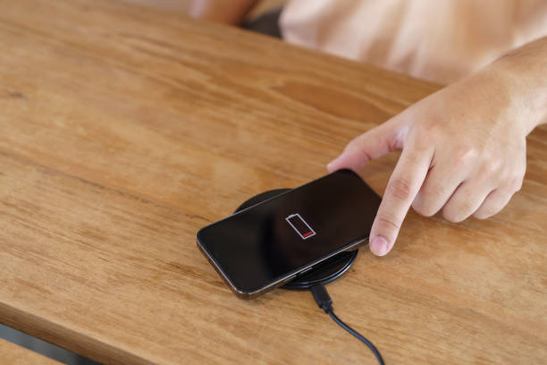 istock Charging mobile phone battery with wireless charging device in the table. Smartphone charging on a charging pad. Mobile phone near wireless charger Modern lifestyle technology concept. 1497435490