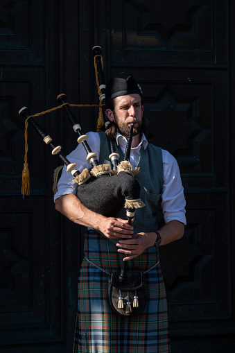 Edinburgh Scotland - June 2 2023: A Man Playing the Bagpipes on a Busy Street in Edinburgh Scotland