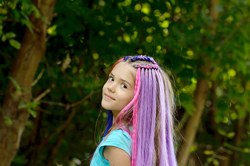 Little girl with stylish haircut of bright colorful hair and braids