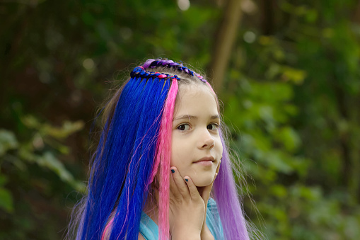 Little girl with stylish haircut of bright colorful hair and braids